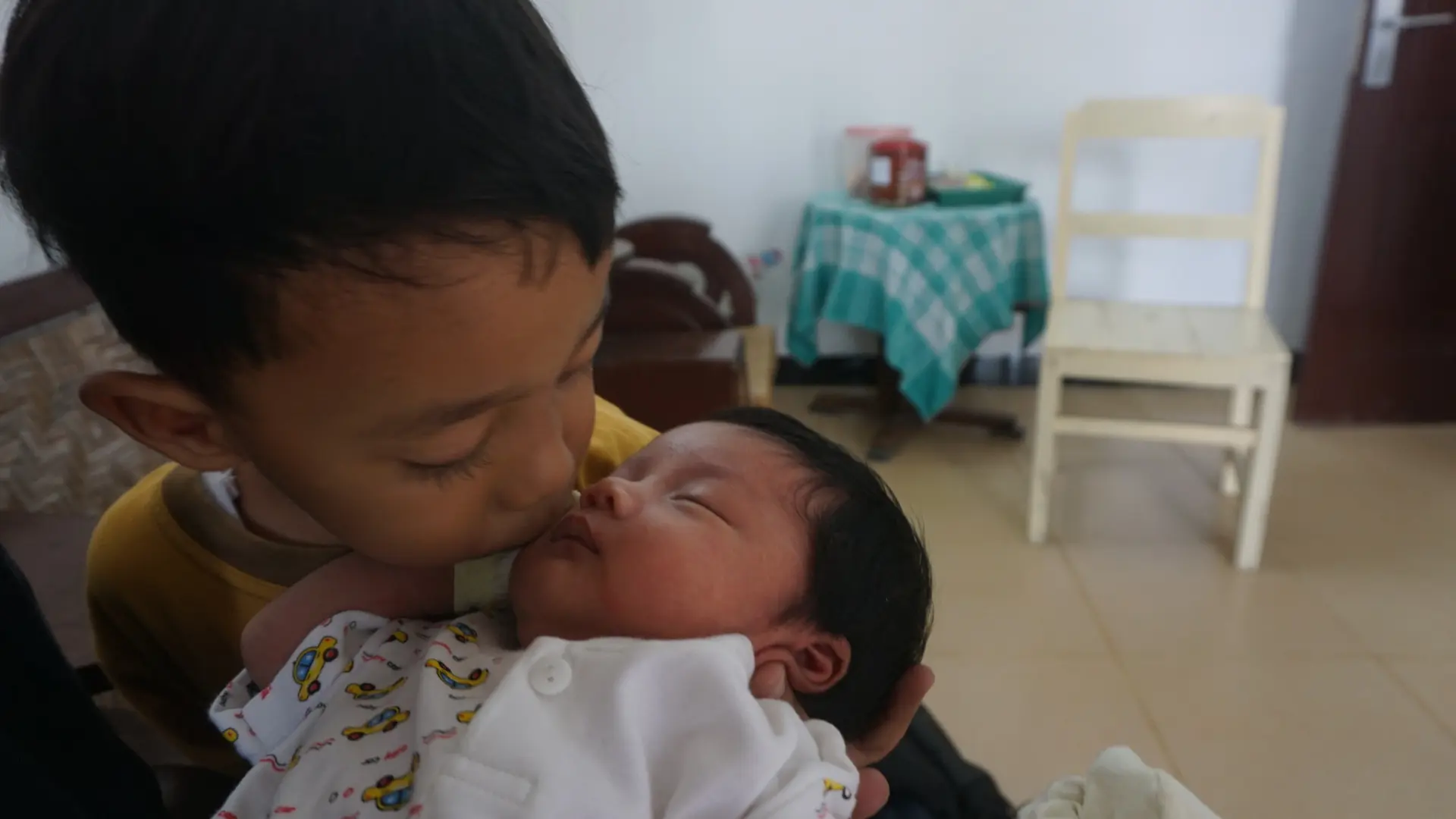 Putra pertama pasangan Kuncora dan Lilis sedang mencium adinda tercinta yang bernama Indonesia.(Liputan6.com/Fajar Abrori)