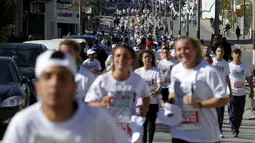 Sejumlah peserta berlari menyusuri tembok pemisah Israel selama Right to Movement Maraton di kota Bethlehem, Palestina, Jumat (1/4). Tembok sejauh 700 km ini dijadikan obyek berlari para peserta. (REUTERS / Ammar Awad)