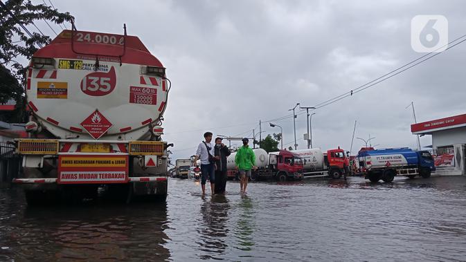 Warga menerobos banjir yang menggenangi daerah Kaligawe, Kota Semarang, Selasa (9/2/2021). Banjir dengan ketinggian 30 hingga 90 cm ini melumpuhkan akses Semarang ke Demak dan sebaliknya. (Liputan6.com/Gholib)