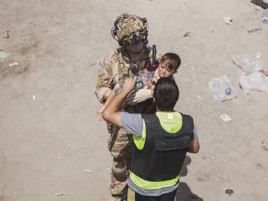 Tentara AS membawa seorang anak di pos pemeriksaan selama evakuasi di Bandara Internasional Hamid Karzai di Kabul, Jumat (20/8/2021). Sejumlah ibu Afghanistan berupaya menyerahkan bayi-bayi mereka pada tentara asing yang berjaga di bandara. (Staff Sgt. Victor Mancilla/U.S. Marine Corps via AP)