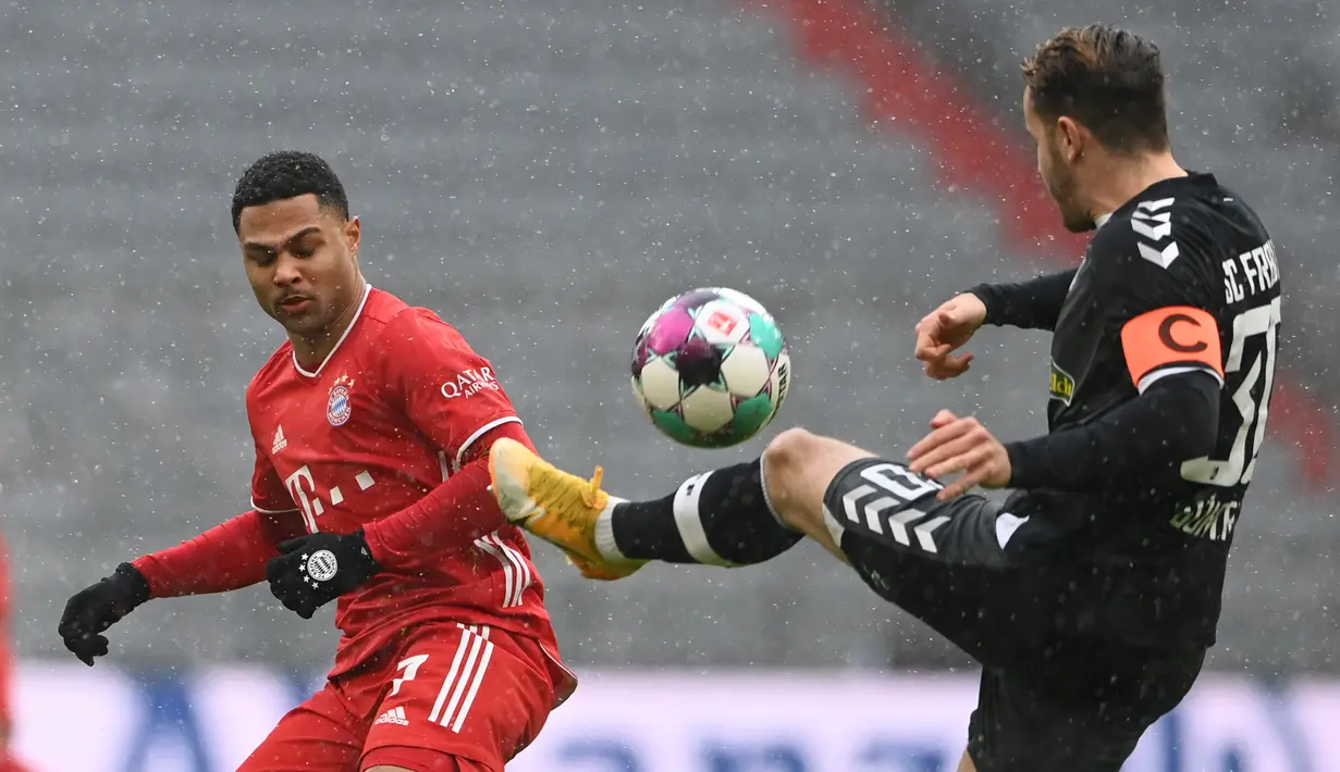 Bek Freiburg, Christian Guenter (kanan) berebut bola dengan gelandang Bayern Munich, Serge Gnabry dalam laga lanjutan Liga Jerman 2020/21 pekan ke-16 di Allianz Arena, Minggu (17/1/2021). Freiburg kalah 1-2 dari Bayern Munich. (AFP/Christof Stache/Pool)