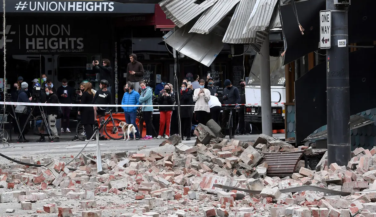 Warga berkumpul di dekat sebuah bangunan yang rusak setelah gempa magnitudo 5,8 di pusat perbelanjaan populer Chapel Street di Melbourne, Rabu (22/9/2021). Dilaporkan, warga Melbourne yang panik berlarian ke jalanan setelah guncangan gempa terasa di gedung-gedung. (William WEST/AFP)
