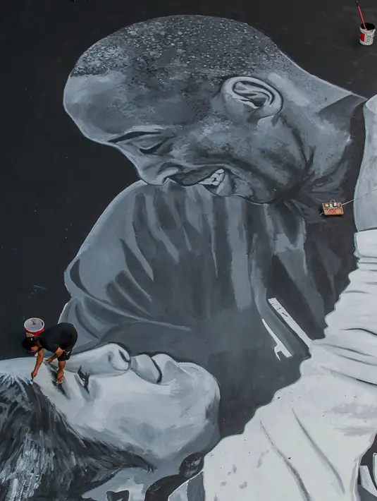 Seorang seniman melukis mural raksasa pada lantai sebuah lapangan basket untuk menghormati mantan bintang NBA Kobe Bryant dan putrinya Gianna di Taguig City, Filipina, Selasa (28/1/2020). Kobe Bryant dan Gianna meninggal dalam kecelakaan helikopter pada 26 Januari 2020. (Xinhua/Rouelle Umali)