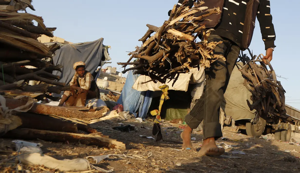 Seorang pria membawa tumpukan kayu di sebuah pasar di Sanaa, Yaman, pada 5 November 2020. Penduduk Yaman beralih menggunakan kayu untuk memasak karena kekurangan pasokan bahan bakar. (Xinhua/Mohammed Mohammed)