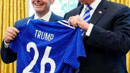Presiden AS Donald Trump berpose dnegan jersey yang diberikan presiden FIFA, Gianni Infantino selama pertemuan di Oval Office Gedung Putih, Selasa (28/8). Presiden FIFA bertemu Trump untuk membahas kesiapan Piala Dunia 2026. (AFP/Mandel Ngan)