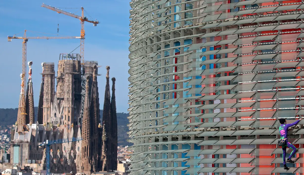 Pendaki pencakar langit, Alain Robert, yang juga dikenal sebagai 'Spiderman Prancis' memanjat Menara Agbar setinggi 144 meter di Barcelona, Rabu (4/3/2020). Aksi itu untuk menyerukan pemerintah dan individu di dunia agar lebih bertanggung jawab dalam menghadapi virus corona COVID-19. (AP/Joan Mateu)