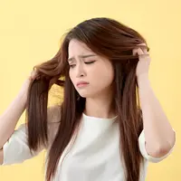 Seorang perempuan tampak memegang rambutnya yang lepek (Foto Dok: Freepik/makistock).