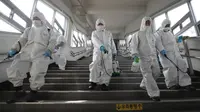 Pekerja memakai alat pelindung semprotan disinfektan untuk membantu mencegah penyebaran Virus Corona COVID-19, di stasiun kereta bawah tanah di Seoul pada 12 Maret 2020. (YONHAP / AFP)