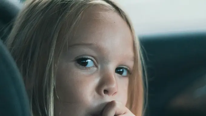 Seorang gadis kecil duduk di kursi belakang mobil