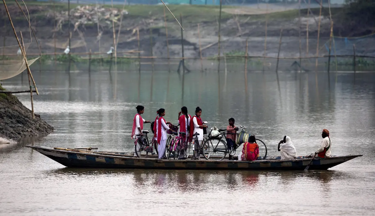 Anak-anak sekolah naik perahu menyeberangi sungai Brahmaputra di desa Kasoshila di pinggiran Gauhati, India (21/10/2019). Brahmaputra adalah salah satu sungai terbesar di Asia, yang melewati wilayah Tibet China, India, dan Bangladesh sebelum konvergen ke Teluk Benggala. (AP Photo/Anupam Nath)