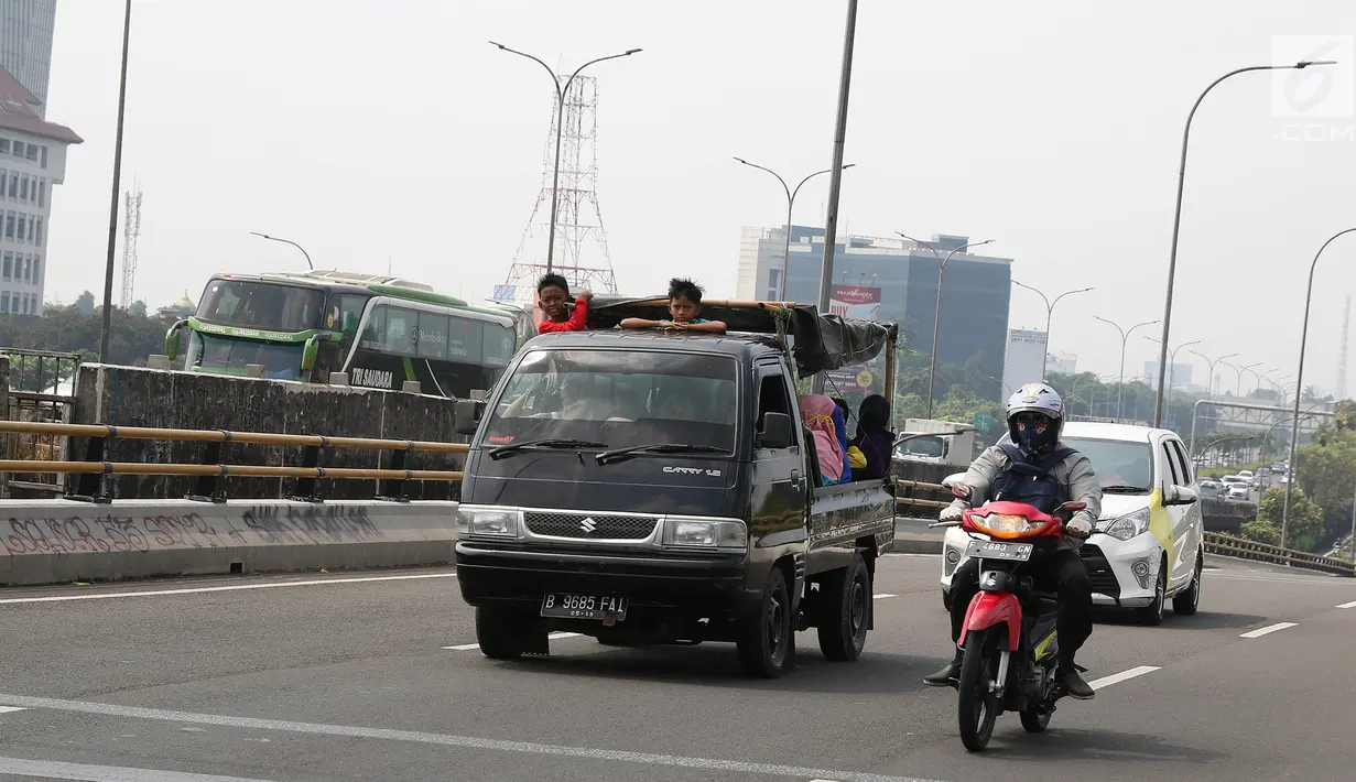 Warga menumpang kendaraan bak terbuka untuk menuju Kebun Binatang Ragunan di kawasan Jakarta, Minggu (9/6/2019). Masyarakat memanfaatkan truk dan mobil bak terbuka untuk bepergian saat libur lebaran karena dianggap lebih hemat biaya. (Liputan6.com/Herman Zakharia)