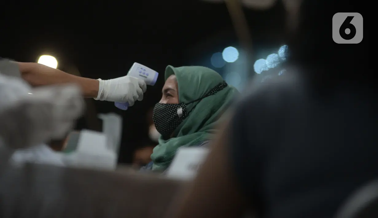 Warga diukur suhu tubuh sebelum Vaksinasi Covid-19 di Kawasan Bulungan, Jakarta, Kamis (24/6/2021).  Vaksinasi Covid-19 keliling tersebut secara massal 147 ribu warga Jadetabek dengan pembatasan mobilitas pengguna jalan pada masa PPKM skal mikro. (merdeka.com/Imam Buhori)