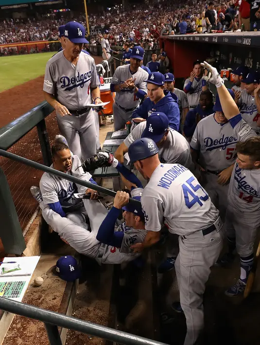 Pemain Los Angeles Dodgers, Cody Bellinger dibantu rekan-rekannya saat terjatuh di tempat istirahat pada pertandingan kelima dalam game 3 dari Divisi Liga Nasional baseball di Phoenix (9/10). (Christian Petersen / Getty Images / AFP)
