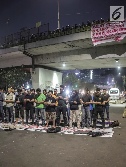 Massa dari Badan Eksekutif Mahasiswa Seluruh Indonesia (BEM SI) melakukan salat magrib disela unjuk rasa di depan gedung DPR/MPR RI, Jakarta, Selasa (1/10/2019). Di sela-sela agenda pelantikan anggota baru DPR RI 2019-2024, gelombang mahasiswa kembali menggelar demo. (Liputan6.com/Faizal Fanani)