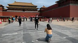 Seorang pria berpose di pintu masuk Kota Terlarang di Beijing, China, Selasa (7/6/2022). Pemerintah melonggarkan beberapa pembatasan Covid-19 dengan sebagian besar museum gedung bioskop, dan pusat kebugaran diizinkan beroperasi hingga 75 persen dari kapasitas. (WANG Zhao / AFP)