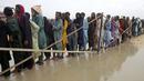 Pengungsi menunggu giliran untuk mendapatkan makanan dan barang-barang lainnya yang dibagikan oleh tentara di sebuah kamp bantuan di daerah yang dilanda banjir di distrik Jamshoro, di Pakistan selatan, Rabu (24/8/2022). Hujan deras telah memicu banjir bandang dan mendatangkan malapetaka di banyak tempat. (AP Photo/Pervez Masih)