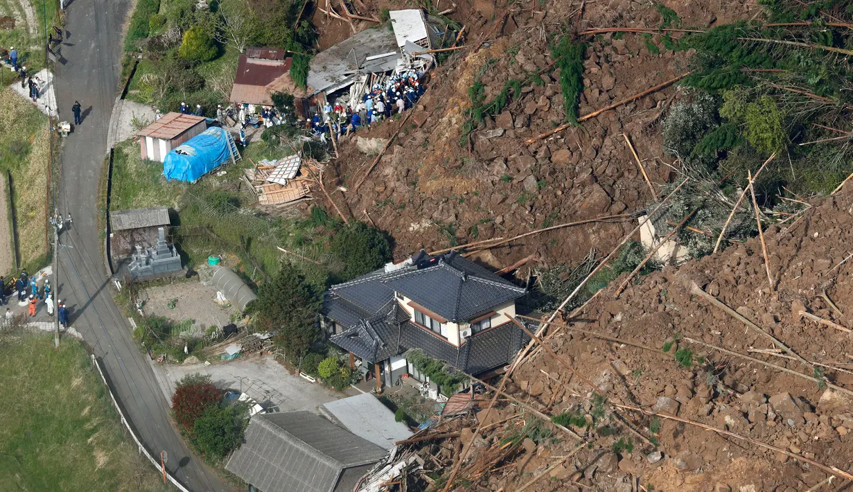 Petugas penyelamat dan polisi melakukan evakuasi di sekitar lokasi terjadinya longsor yang menghantam rumah hunian di Nakatsu, Prefektur Oita, Jepang (11/4). (Takuto Kaneko/Kyodo News via AP)
