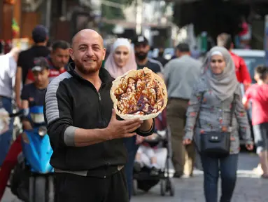 Seorang pedagang Suriah memperlihatkan panekuk tradisional yang dikenal sebagai "Naaem" yang biasa disajikan selama Ramadhan, di Shaqhoor Damaskus pada 28 April 2021. Tahun demi tahun, makanan Ramadhan menjadi lebih hemat di Suriah yang dilanda perang dan ekonomi yang memburuk. (LOUAI BESHARA/AFP)