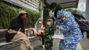 Perserta yang tergabung dalam Forum Kader Bela Negara DKI Jakarta membagikan bunga dan masker kepada warga di Jalan Thamrin, Jakarta, Rabu (22/12/2021). Aksi tersebut merupakan bentuk apresiasi terhadap kaum perempuan terutama pada peringatan Hari Ibu. (Liputan6.com/Faizal Fanani)