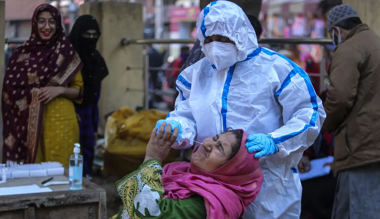 Petugas kesehatan mengambil sampel swab seorang perempuan di sebuah pasar di Jammu, India, Rabu (29/12/2021). Di India, yang telah kembali normal setelah dihantam tsunami COVID-19 tahun ini, omicron sekali lagi menimbulkan ketakutan, dengan lebih dari 700 kasus dilaporkan. (AP Photo/Channi Anand)