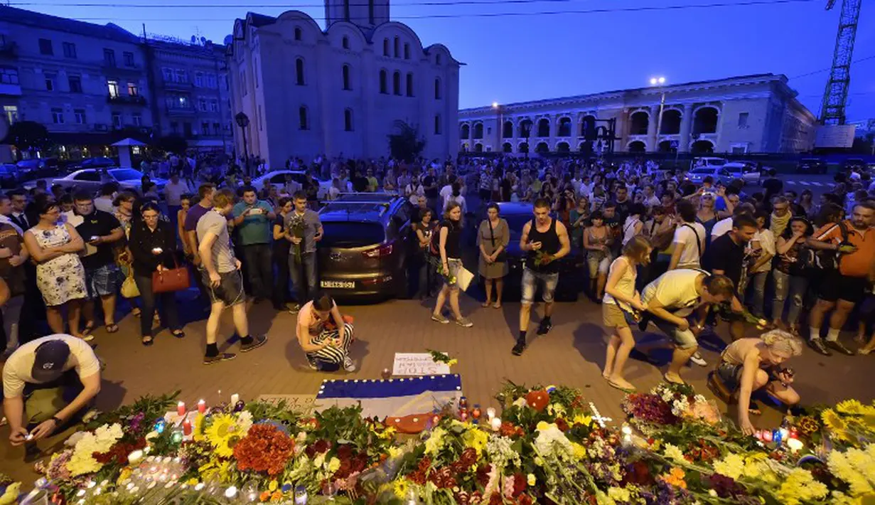 Sejumlah warga meletakan karangan bunga lilin sebagai ungkapan belasungkawa atas jatuhnya pesawat Malaysia Airlines MH-17 di Ukraina, Jumat (17/7/14). (AFP PHOTO/Sergei Supinsky)