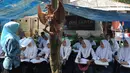 Guru mengajar siswa kelas 8 SMP  1 Cijeruk Terbuka di tempat belajar beratapkan terpal di halaman rumah warga di Kampung Cijeruk RT 002/005, Desa Palasari, Kecamatan Cijeruk, Kabupaten Bogor, Jawa Barat, Senin (2/9/2019). (merdeka.com/Arie Basuki)