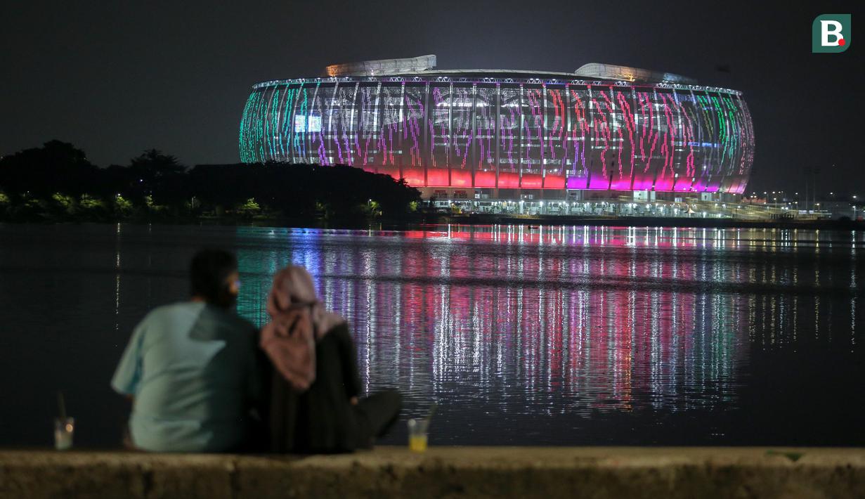 <p>Sepasang kekasih tengah menikmati Jakarta International Stadium (JIS) yang dilihat dari Danau Cincin, Papango, Tanjung Priok, Jakarta Utara, 19 April 2022. (Bola.com/Bagaskara Lazuardi)</p>