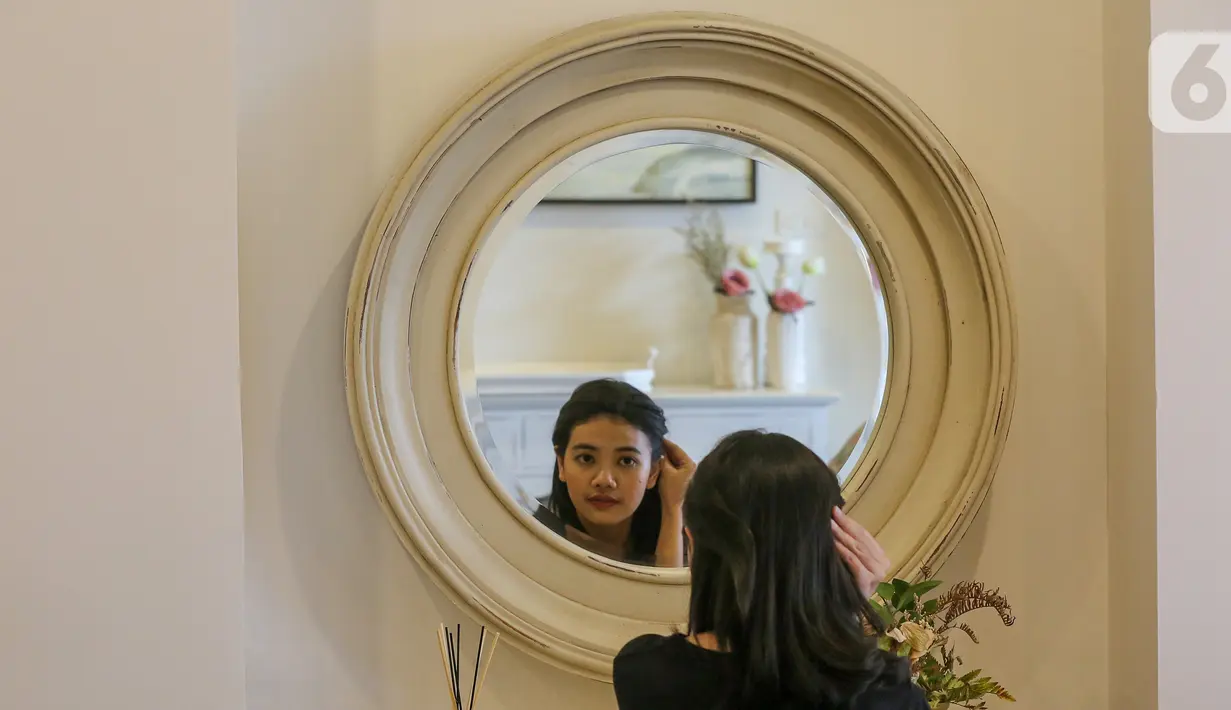 Pengunjung merapikan rambut di cermin dari jenis kayu mahoni di Bramble Furniture, Kemang Timur, Jakarta, Selasa (28/1/2020). Furniture yang diproduksi di Solo tersedia lebih dari 50 pilihan warna yang dapat dikombinasikan dengan lebih dari 100 opsi finish. (Liputan6.com/Fery Pradolo)
