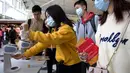 Para pelancong mengenakan masker wajah saat berada di Bandara Internasional Hong Kong di Hong Kong, Selasa (21/1/2020). Masker terjual habis dan pemeriksaan suhu di bandara dan stasiun kereta api menjadi norma baru di China menyusul merebaknya wabah virus corona.  (AP/Ng Han Guan)