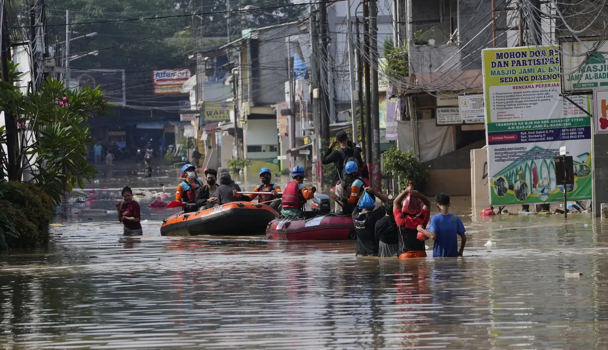 Warga duduk dalam perahu karet saat mereka mengungsi ke tempat yang lebih tinggi selama banjir di Bekasi, Jawa Barat, Kamis (17/2/2022). Hujan deras yang dikombinasikan dengan perencanaan pembuangan limbah kota yang buruk sering menyebabkan banjir besar. (AP Photo/Achmad Ibrahim)