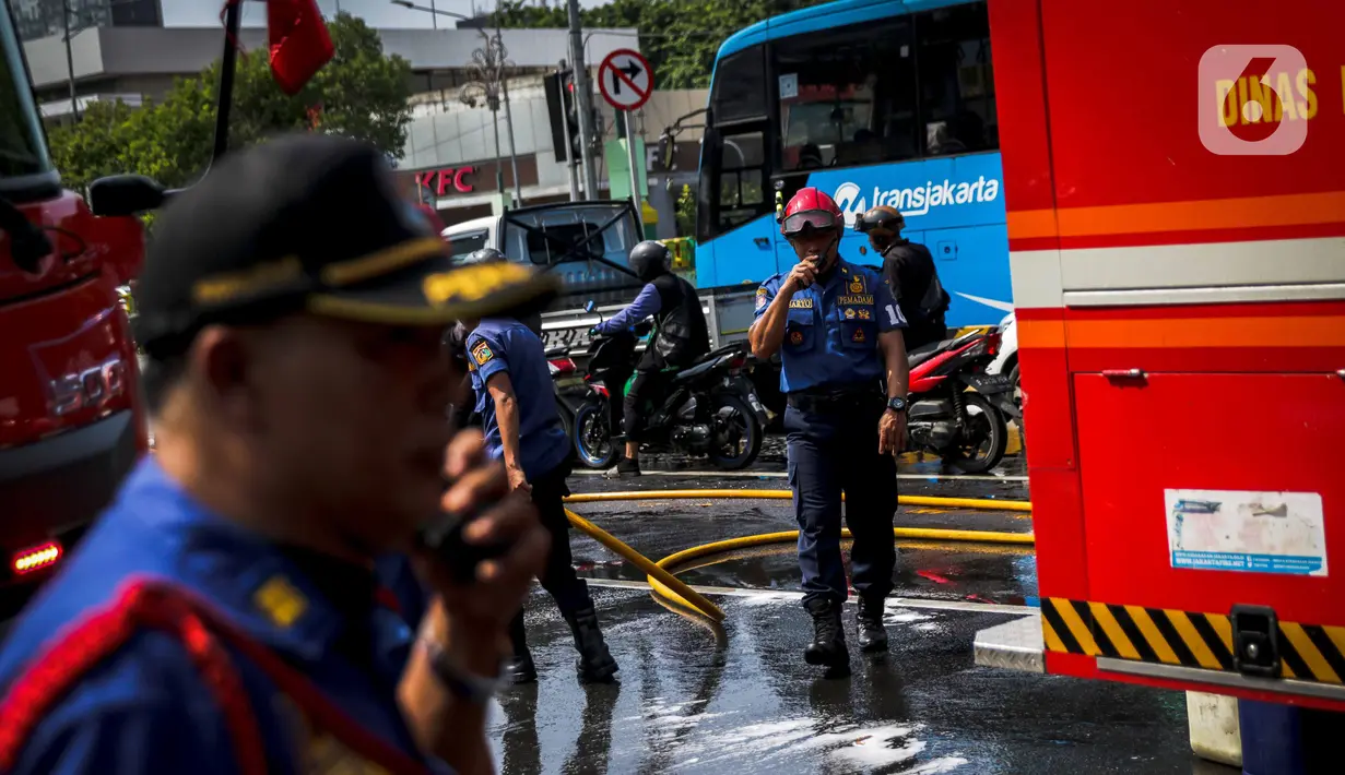 Sejumlah personil pemadam kebakaran membersihkan tumpah oli yang terjadi di Jalan Veteran depan Gedung Krida Bakti, Jakarta, Kamis (16/1/2020). Petugas damkar  melakukan pembersihan dengan cairan deterjen maupun campuran khusus agar jalan tersebut tidak lagi licin. (Liputan6.com/Faizal Fanani)