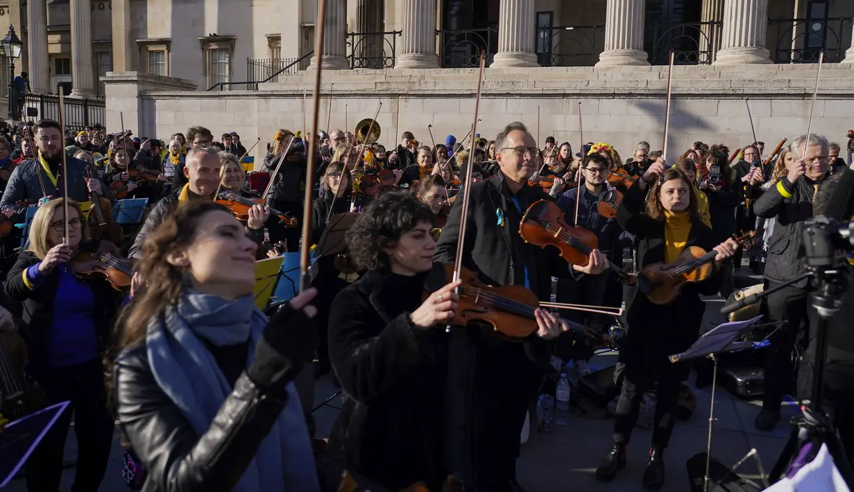 Anggota orkestra bermain sebagai bagian dari demonstrasi anti-perang menyusul serangan Rusia terhadap Ukraina di Trafalgar Square, London, Minggu (6/3/2022).  Flashmob yang terdiri dari 200 musisi klasik itu untuk menunjukkan dukungan terhadap Ukraina setelah invasi Rusia. (AP Photo/Alberto Pezzali)