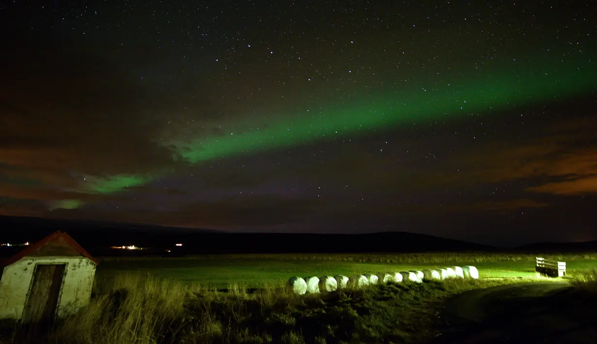 Aurora borealis atau Cahaya Utara terlihat di atas lahan pertanian dekat air terjun Godafoss di Thingeyjarsveit, Islandia, 14 Oktober 2018. Lukisan abstrak alam semesta dari tabrakan spektrum warna Aurora Borealis begitu spektakuler. (Mariana SUAREZ/AFP)