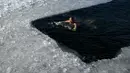Seorang perenang es berenang di danau beku pada hari musim dingin di Beijing  (6/1/2021). Berenang di musim dingin adalah kegiatan olahraga yang jarang dijumpai kecuali di beberapa negara dengan musim dingin yang cukup panjang. (AFP/Wang Zhao)
