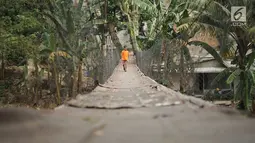 Seorang anak melintasi jembatan gantung semi permanen di kawasan Srengseng Sawah, Jakarta Selatan, Sabtu (24/8/2019). Warga terpaksa memanfaatkan jembatan itu untuk menyeberangi Sungai Ciliwung kendati kondisinya memprihatinkan dan berisiko menyebabkan kecelakaan. (Liputan6.com/Immanuel Antonius)