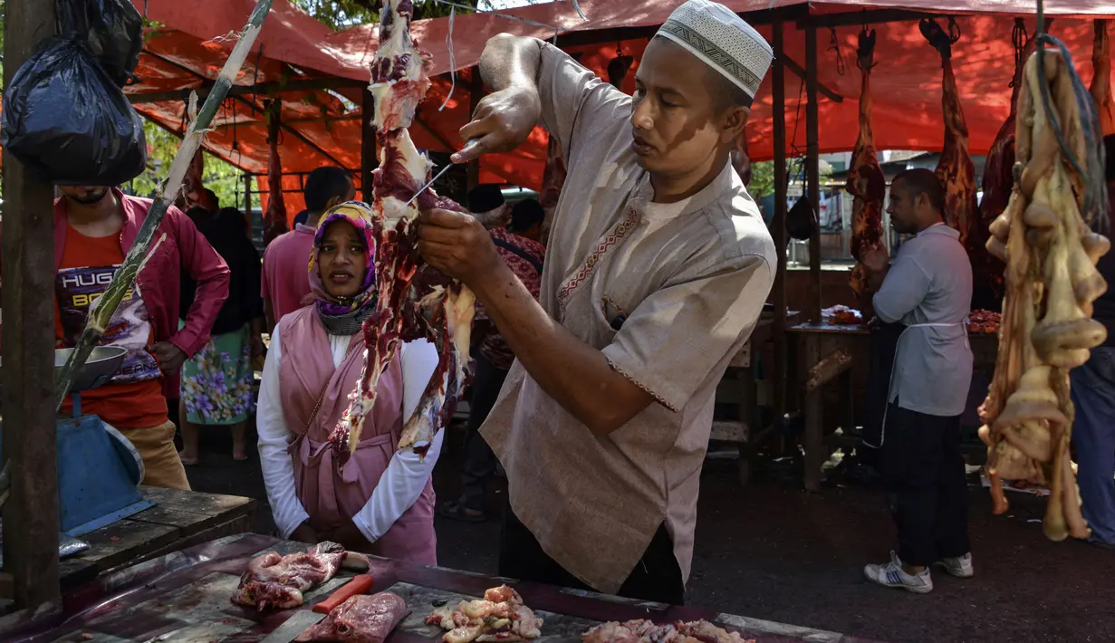 Pedagang memotong daging sapi dagangannya pada perayaan tradisi Meugang Ramadan 1440 Hijriah di Banda Aceh, 4 Mei 2019. Meugang merupakan tradisi turun temurun masyarakat Aceh dengan membeli, mengolah, hingga menyantap daging bersama keluarga. (CHAIDEER MAHYUDDIN/AFP)