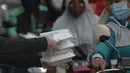 Warga menerima pembagian nasi bungkus gratis di Posko Perjuangan Rakyat (POSPERA), Jakarta, Rabu (10/3/2021). Pembagian 500 nasi bungkus beserta masker dan vitamin secara gratis setiap harinya dalam bentuk meringankan beban warga di tengah pandemi Covid-19. (merdeka.com/Imam Buhori)