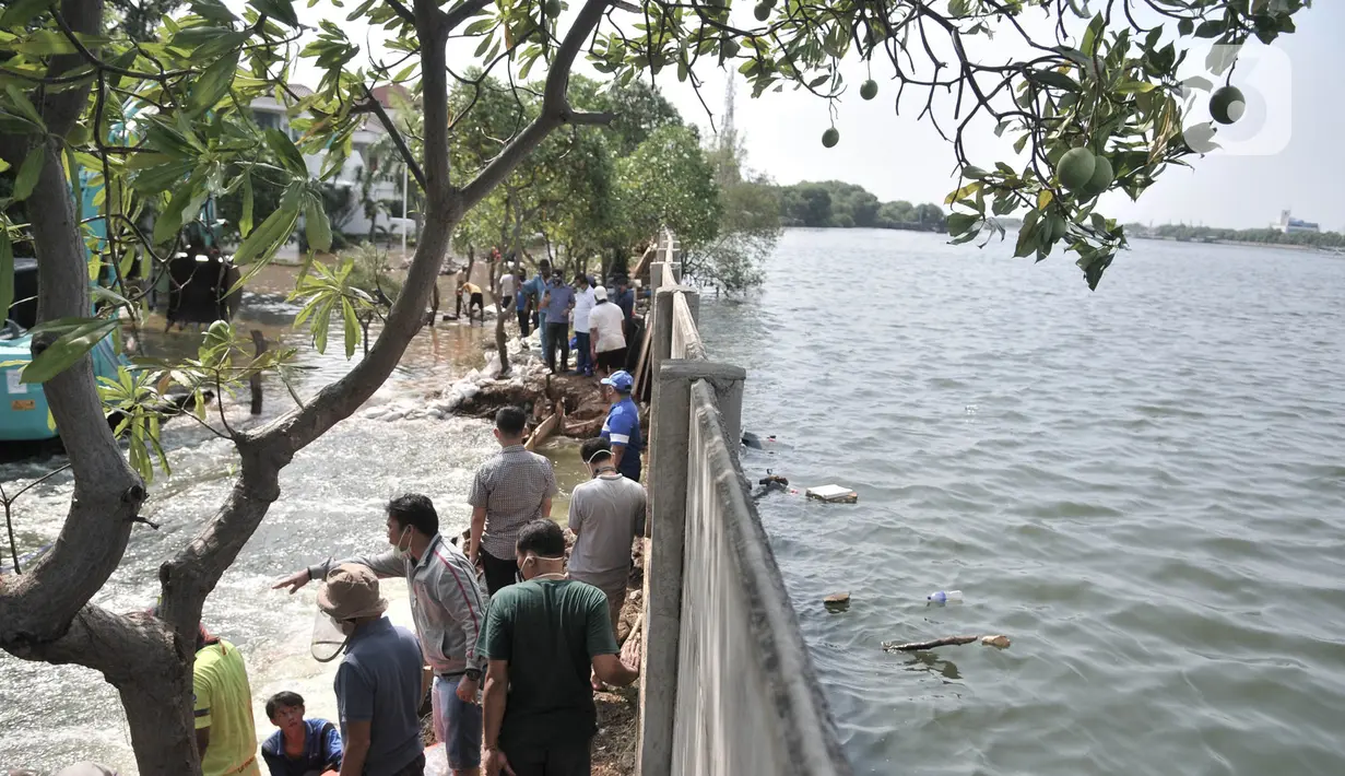 Pekerja menyelesaikan perbaikan tanggul jebol di Kompleks Perumahan Pantai Mutiara, Pluit, Jakarta, Minggu (7/6/2020). Tanggul jebol dengan panjang sekitar 10 meter yang terjadi bersamaan air pasang pada Sabtu (6/6) menyebabkan perumahan tersebut terendam banjir rob. (Liputan6.com/Iqbal S. Nugroho)