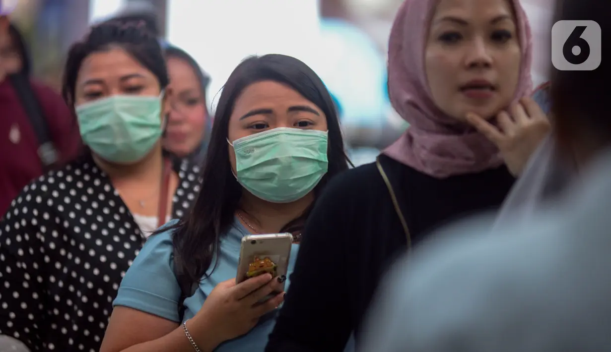 Calon penumpang kereta api mengenakan masker saat berada di Stasiun Gambir, Jakarta Pusat, Jumat (31/01). Dalam rangka pencegahan Virus Corona, PT Kereta Api Indonesia (persero) melakukan sosialisasi kepada penumpang dengan membagi-bagikan masker di stasiun Gambir. (merdeka.com/Imam Buhori)