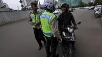 Aparat kepolisian lalu lintas saat memberhentikan pengendara motor gede yang menerobos Jalan MH Thamrin, Jakarta, Minggu (18/1/2015). (Liputan6.com/Miftahul Hayat)