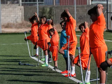 Anak-anak Palestina yang diamputasi melakukan pemanasan dalam sesi pelatihan sepak bola, yang diatur oleh Komite Palang Merah Internasional (ICRC) setelah pembatasan penyakit coronavirus (COVID-19) mereda, di Deir al-Balah di Jalur Gaza tengah (14/7/2020). (AFP/Mahmud Hams)