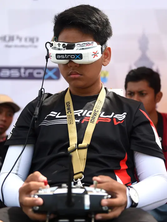 Seorang pilot muda mengendalikan drone balapnya dengan kacamata headset FPV selama acara FAI Drone Racing World Cup di Denpasar di pulau resor Indonesia Bali (7/4). (AFP Photo/Sonny Tumbelaka)