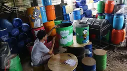 Seorang pengrajin melukis tong sampah bekas limbah di kawasan serpong, Tangerang Selatan, Senin (20/3). Berkat tangan kreatif perajin, tong dari limbah pabrik tersebut berhasil diubah menjadi tempat sampah cantik. (Liputan6.com/Helmi Afandi)