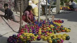 Perajin mengatur pot minyak tembikar atau diyas yang disimpan untuk dikeringkan menjelang Diwali, festival lampu Hindu, di luar bengkel di Hyderabad (4/11/2020). Orang-orang berpartisipasi dalam acara ini dengan penuh sukacita. (AFP Photo/Noah Seelam)