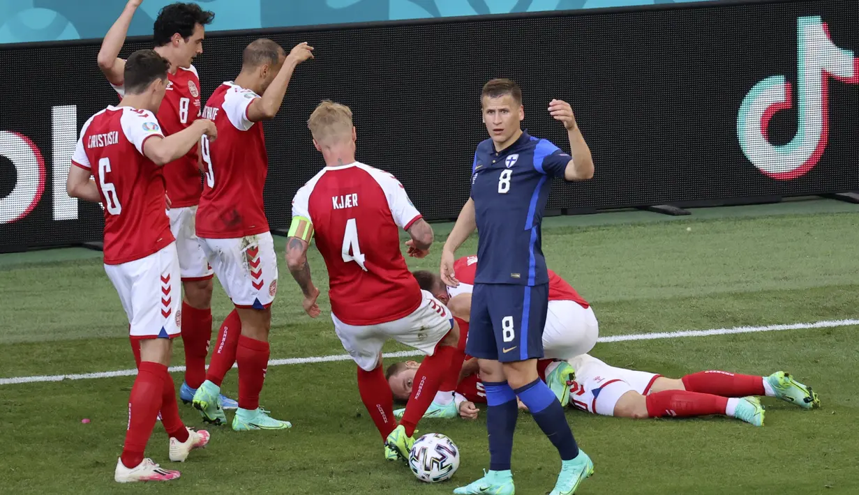 Para pemain Denmark mendatangi rekannya Christian Eriksen yang pingsan pada laga Denmark vs Finlandia di Grup B Euro 2020 di Parken Stadium, Copenhagen, Sabtu (12/6/2021). Eriksen tiba-tiba terjatuh dan kehilangan kesadaran saat hendak menyambut lemparan ke dalam. (Wolfgang Rattay/Pool via AP)