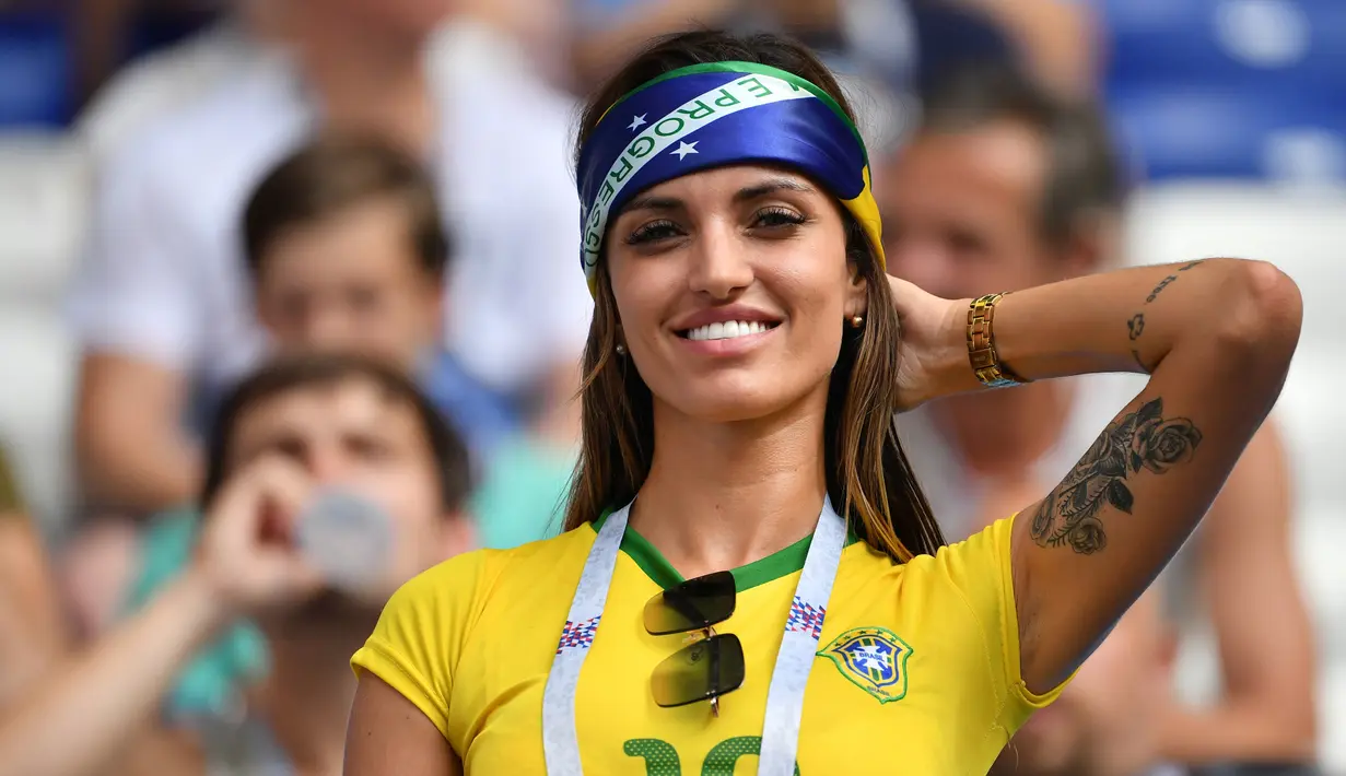 Suporter wanita Brasil berpose sambil tersenyum menunggu pertandingan antara Brasil melawan Meksiko pada 16 besar Piala Dunia 2018 di Samara Arena, Rusia (2/7). Brasil berhasil mengalahkan Meksiko 2-0. (AFP Photo/Emmanuel Dunand)