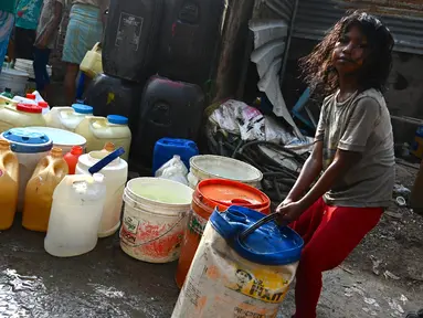 Seorang gadis menyeret ember berisi air yang dikumpulkan dari truk tangki air perusahaan kota di lingkungan berpenghasilan rendah di New Delhi pada Kamis (3/6/2021). Pada tahun 2018, lebih dari 600 juta orang di India tidak memiliki akses air bersih yang cukup. (Money SHARMA / AFP)