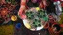 Seorang pembuat tembikar menuangkan lilin ke lampu tanah jelang Festival Diwali di sepanjang pinggir jalan di New Delhi, India, 18 Oktober 2022. Festival Diwali atau dalam agama Hindu berarti Festival Cahaya melambangkan kemenangan baik atas keburukan, dan lampu atau pelita dinyalakan sebagai tanda perayaan serta harapan umat manusia. (Sajjad HUSSAIN/AFP)