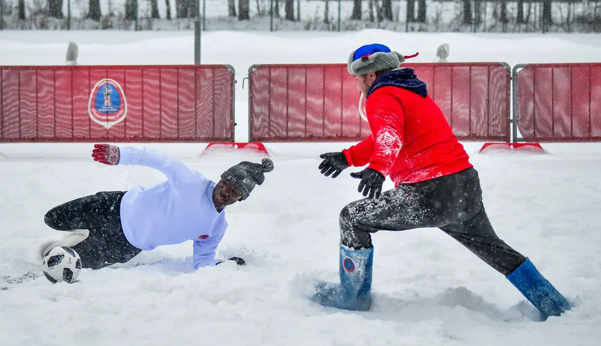 Pemain berebut bola saat pertandingan persahabatan antara wartawan dan mahasiswa asing di lapangan bersalju di Nizhny Novgorod, Rusia, Minggu (21/1). (AFP PHOTO/Mladen ANTONOV)