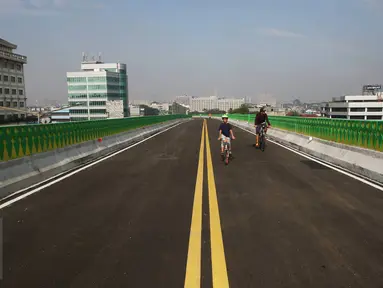 Seorang anak ditemani orang tuanya bersepeda di sepanjang jalan layang (elevated) Transjakarta rute Cileduk-Tendean di Jakarta, Minggu (26/2). Belum beroperasinya jalan layang tersebut dimanfaatkan warga untuk berolahraga. (Liputan6.com/Immanuel Antonius)
